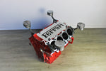 Load image into Gallery viewer, Ferrari engine block coffee table finished in red without its glass top and the Ferrari logo displayed in the center.
