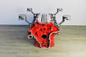 Ferrari engine block coffee table finished in red without its glass top, the Ferrari logo displayed in the center.