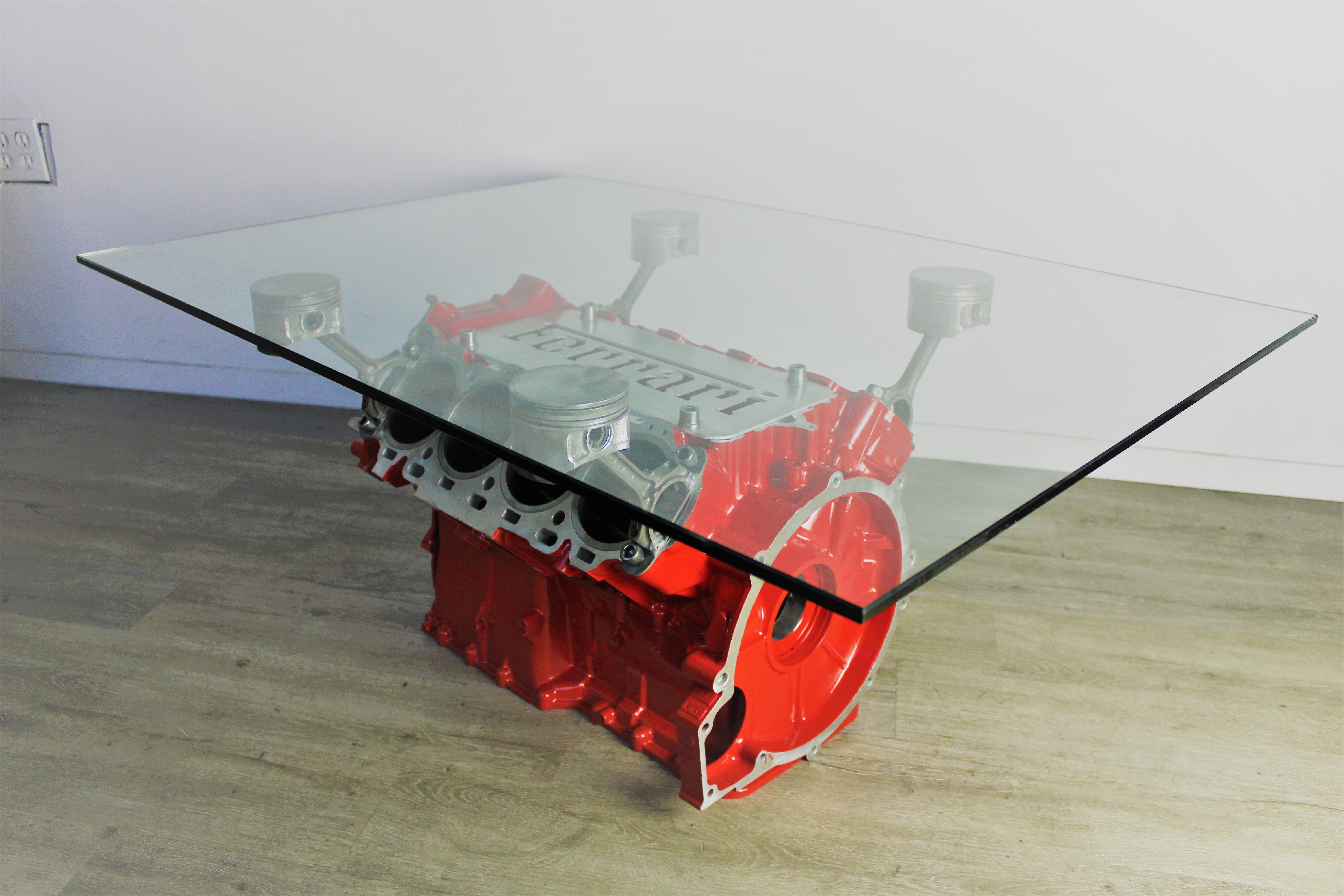 Ferrari engine block coffee table finished in red with a rectangular glass top.
