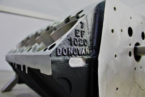 Close-up view of the side of a Top Fuel aluminum engine block coffee table finished in black and silver, engraved with "7, EF, 1020, Donovan"