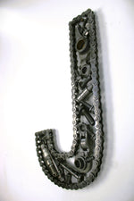Load image into Gallery viewer, A letter J made out of real car parts, outlined with a timing chain.
