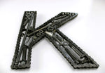 Load image into Gallery viewer, Close-up view of a letter K made out of real car parts, outlined with a timing chain.
