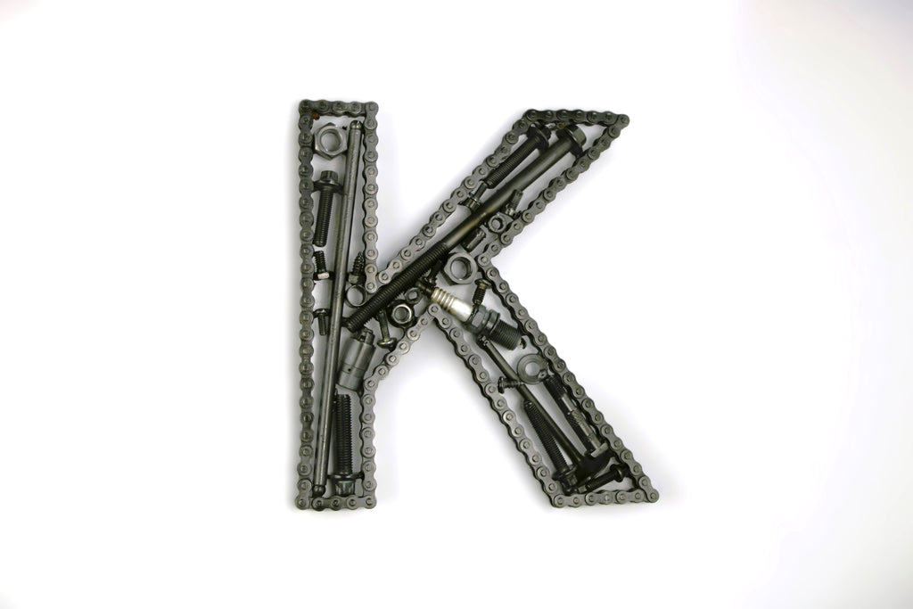 A letter K made out of real car parts, outlined with a timing chain.