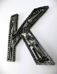 A letter K made out of real car parts, outlined with a timing chain.