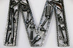 Load image into Gallery viewer, Close-up view of a letter M made out of real car parts, outlined with a timing chain.

