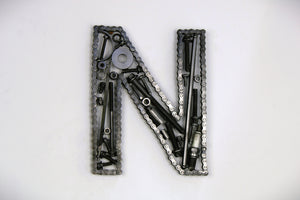 A letter N made out of real car parts, outlined with a timing chain.