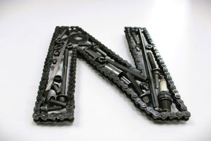 A letter N made out of real car parts, outlined with a timing chain.
