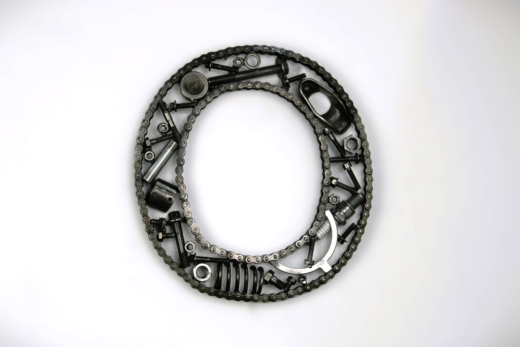 A letter O made out of real car parts, outlined with a timing chain.