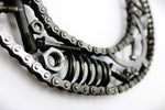 Load image into Gallery viewer, Close-up view of a letter O made out of real car parts, outlined with a timing chain.
