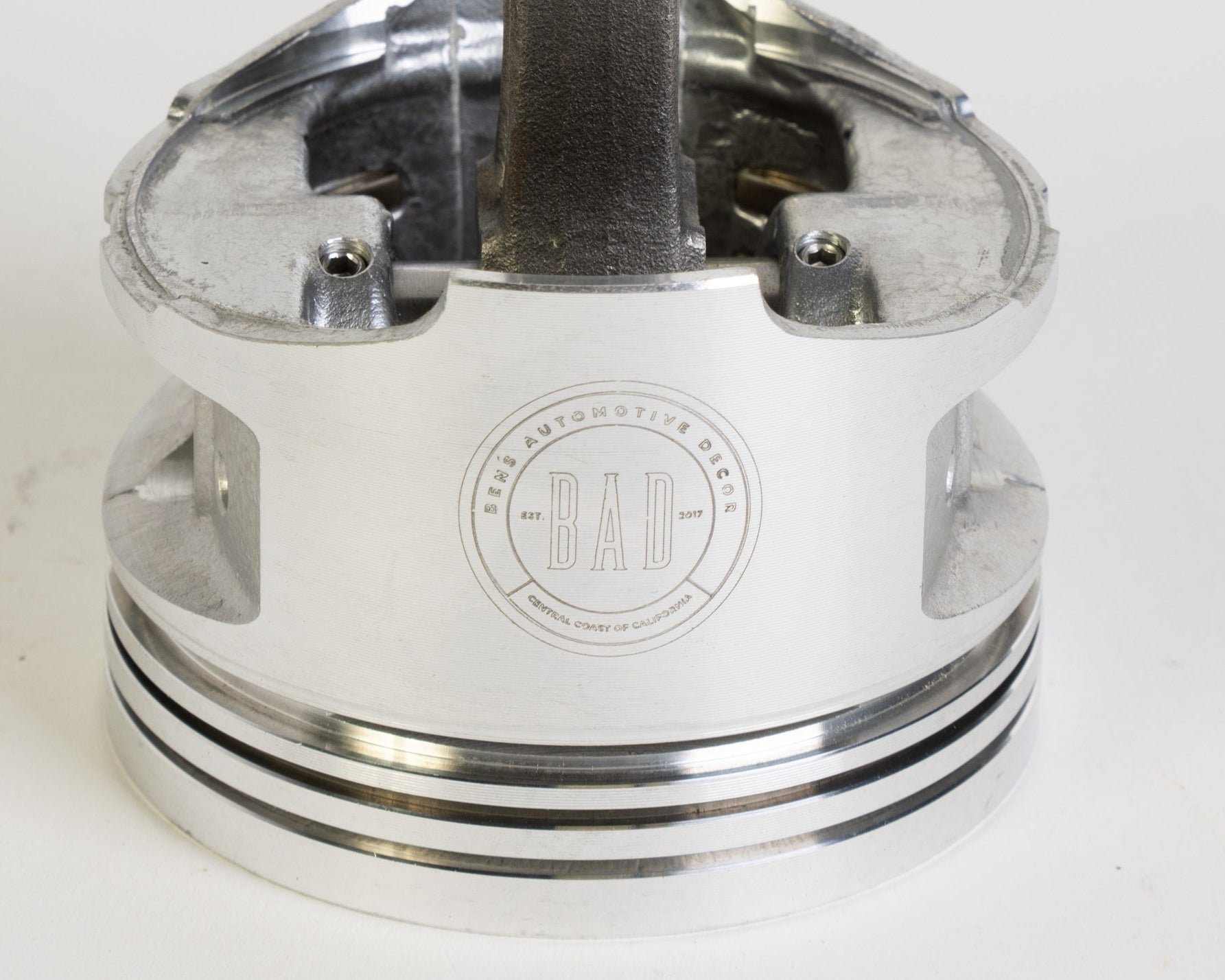 Metal piston with 'BAD' branding on a white background