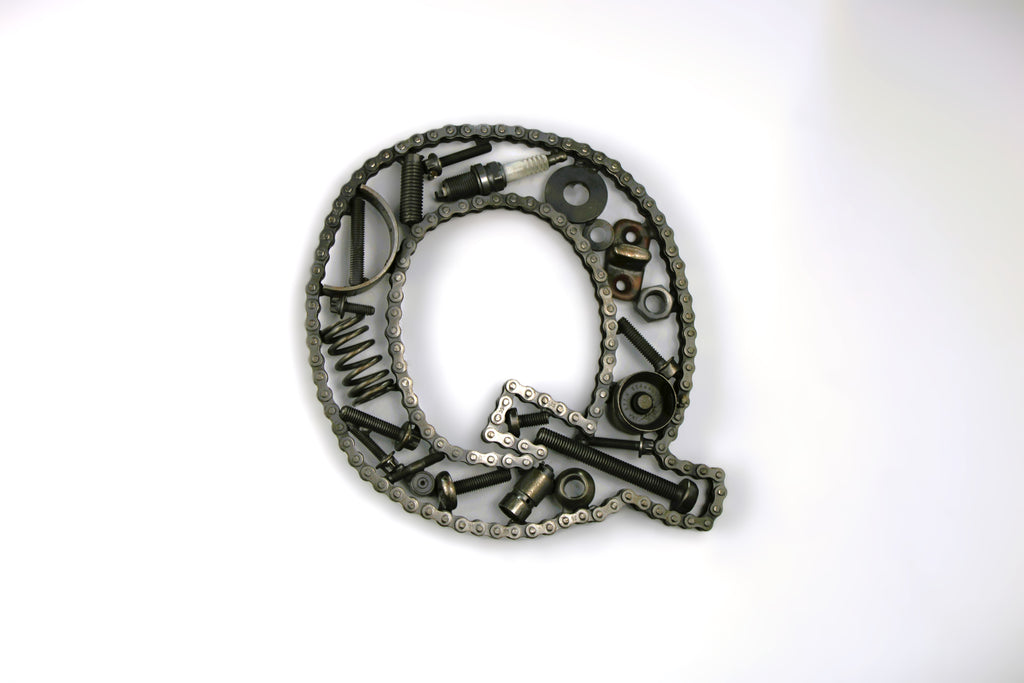 A letter Q made out of real car parts, outlined with a timing chain.