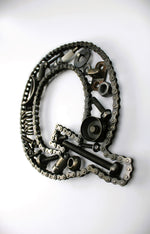 Load image into Gallery viewer, A letter Q made out of real car parts, outlined with a timing chain.
