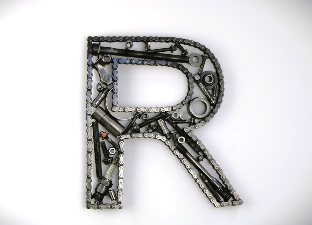 A letter R made out of real car parts, outlined with a timing chain.