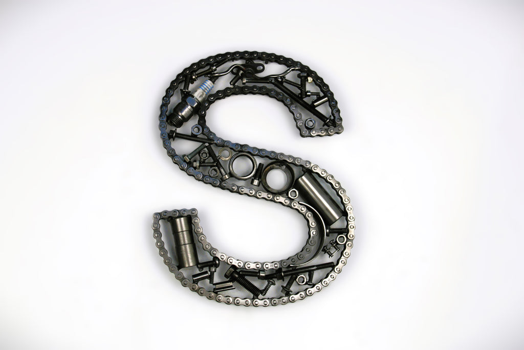A letter S made out of real car parts, outlined with a timing chain.