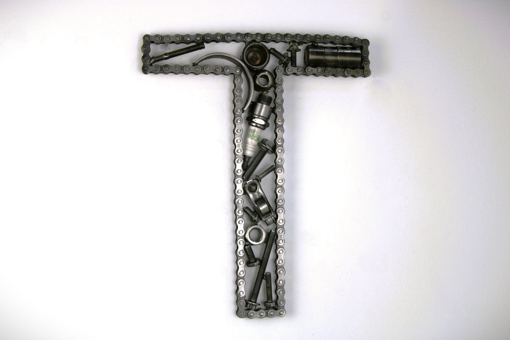 A letter T made out of real car parts, outlined with a timing chain.