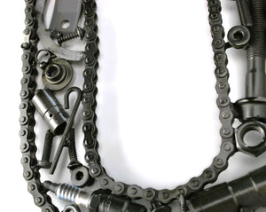 Close-up view of a letter U made out of real car parts, outlined with a timing chain.