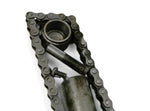 Load image into Gallery viewer, Close-up view of a letter V made out of real car parts, outlined with a timing chain.
