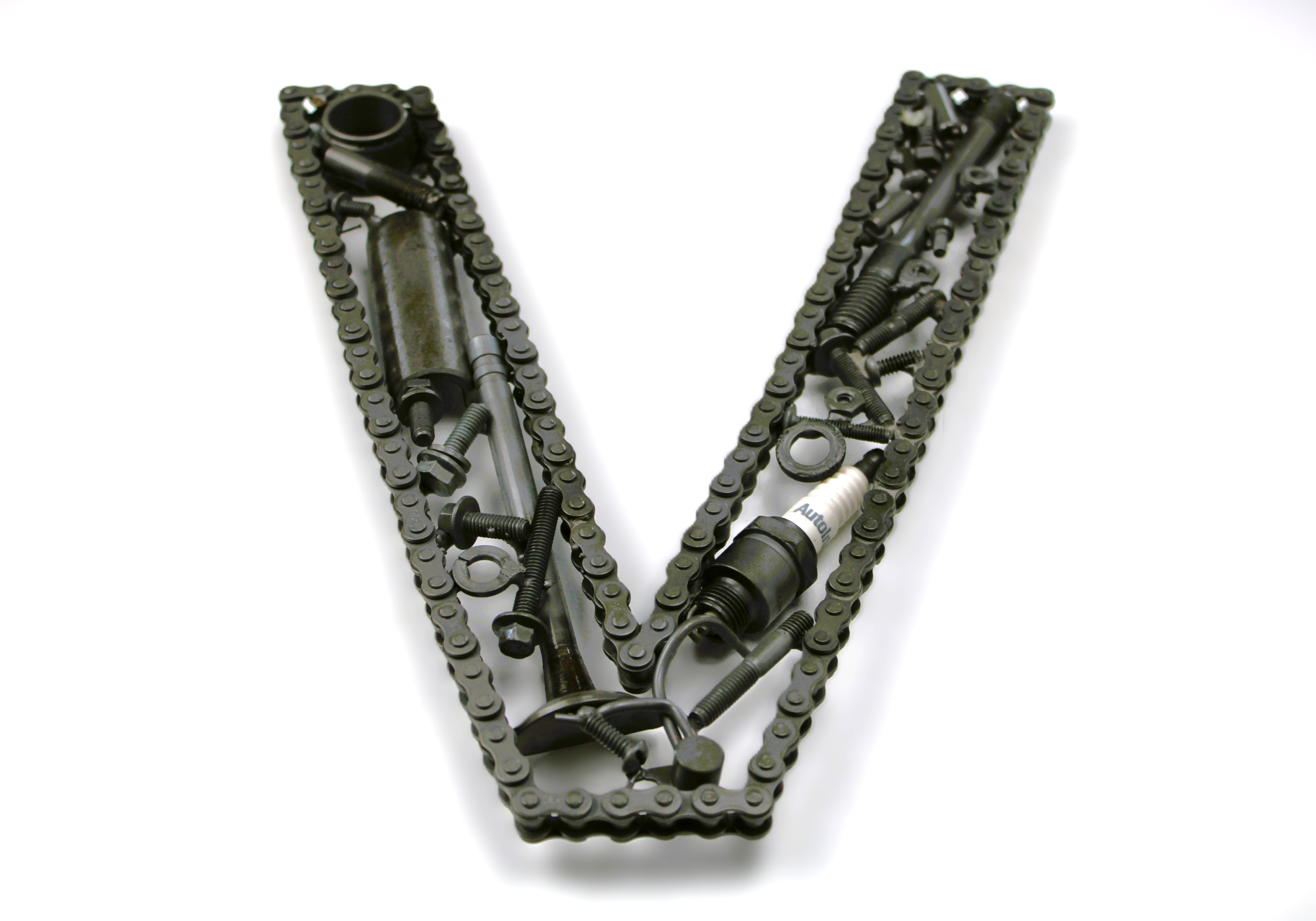 Close-up view of a letter V made out of real car parts, outlined with a timing chain.