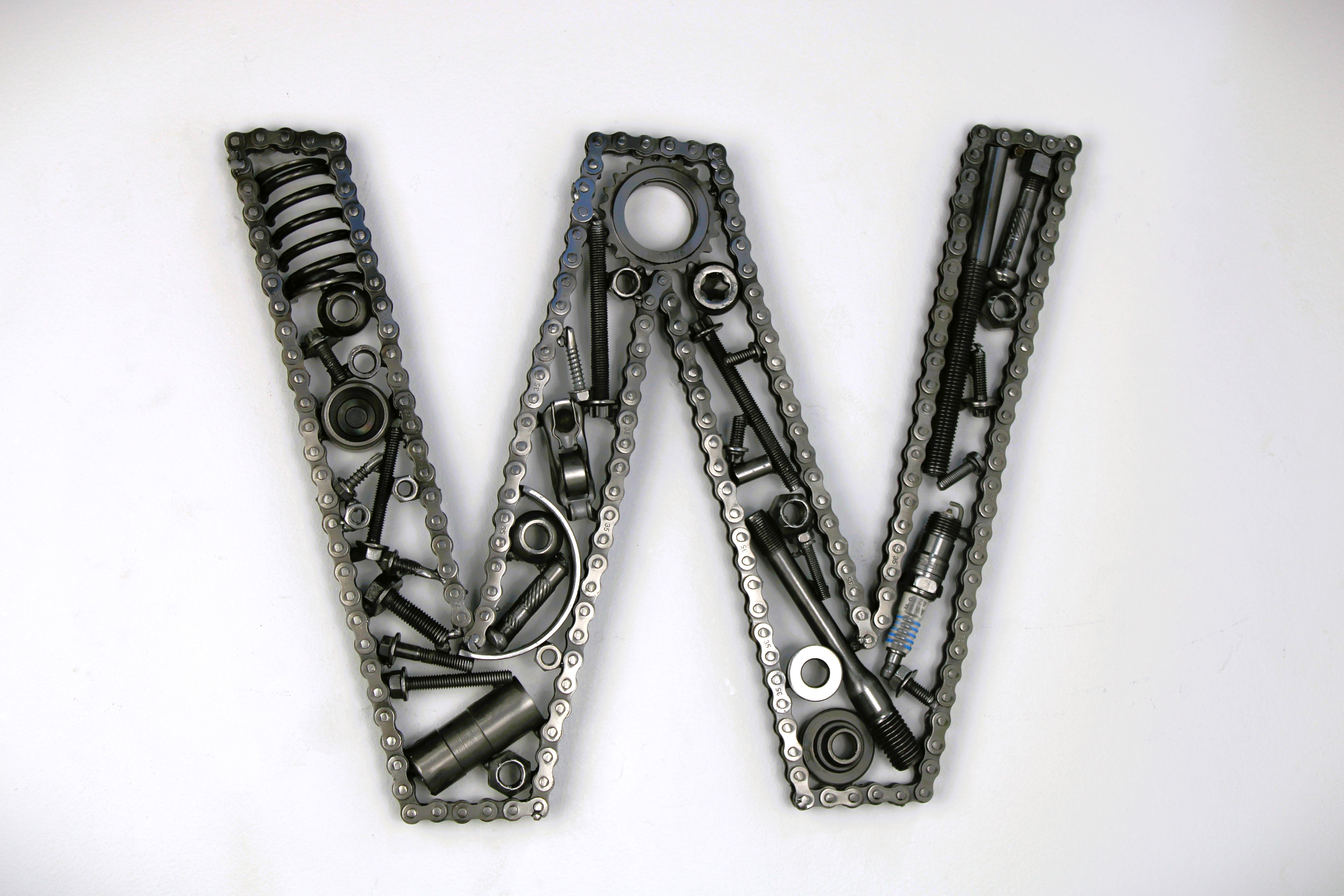 A letter W made out of real car parts, outlined with a timing chain.