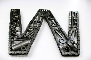 Close-up view of a letter W made out of real car parts, outlined with a timing chain.