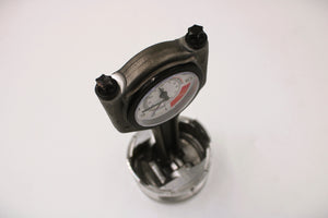 A polished car piston clock with a black clock ring and white and red RPM clock face.