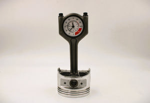 A polished car piston clock with a black clock ring and white and red RPM clock face.