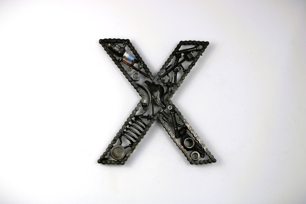 A letter X made out of real car parts, outlined with a timing chain.