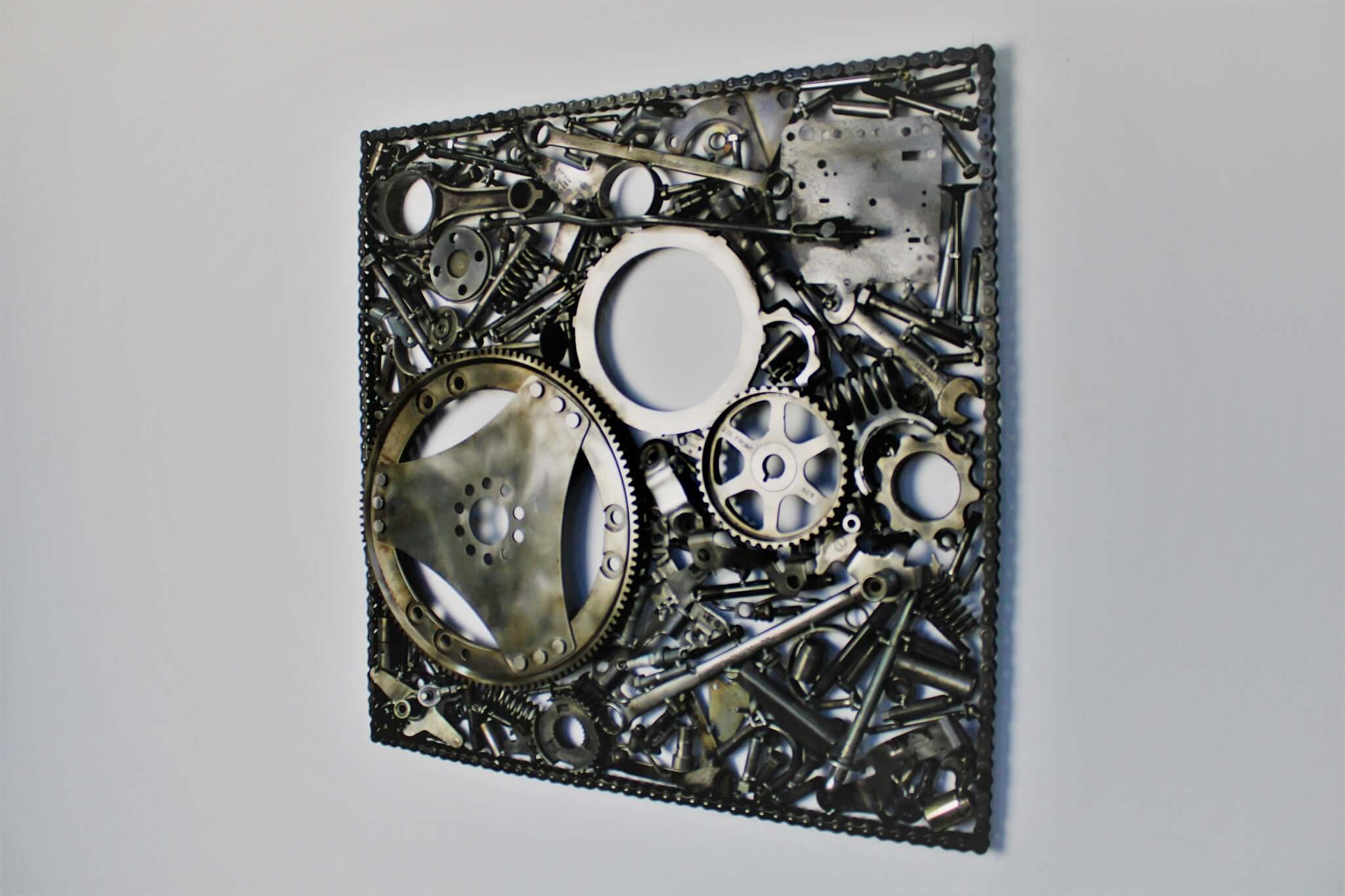Handcrafted metal wall art piece outlined with timing chain and filled in entirely with polished genuine car engine components.