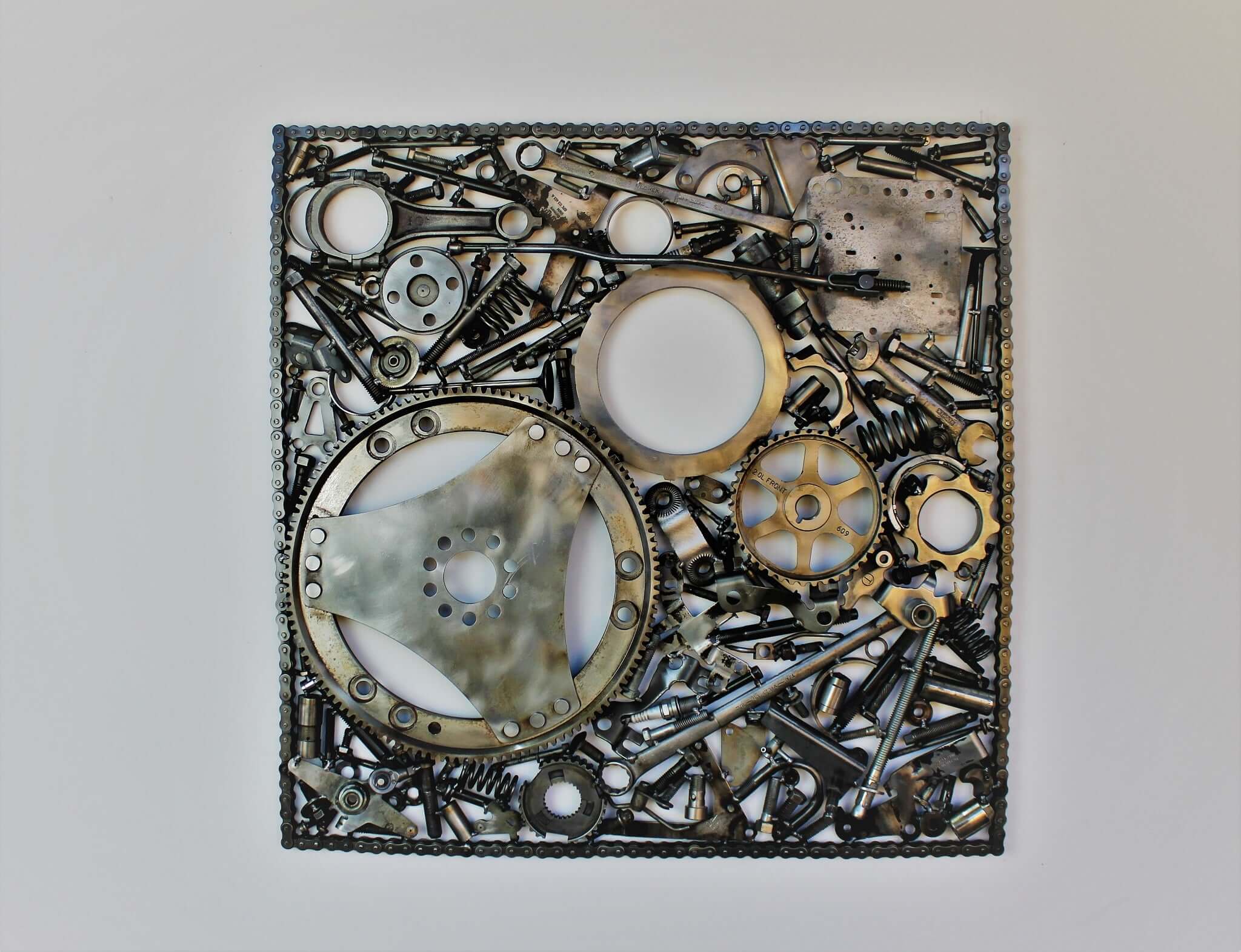 Handcrafted metal wall art piece outlined with timing chain and filled in entirely with polished genuine car engine components.