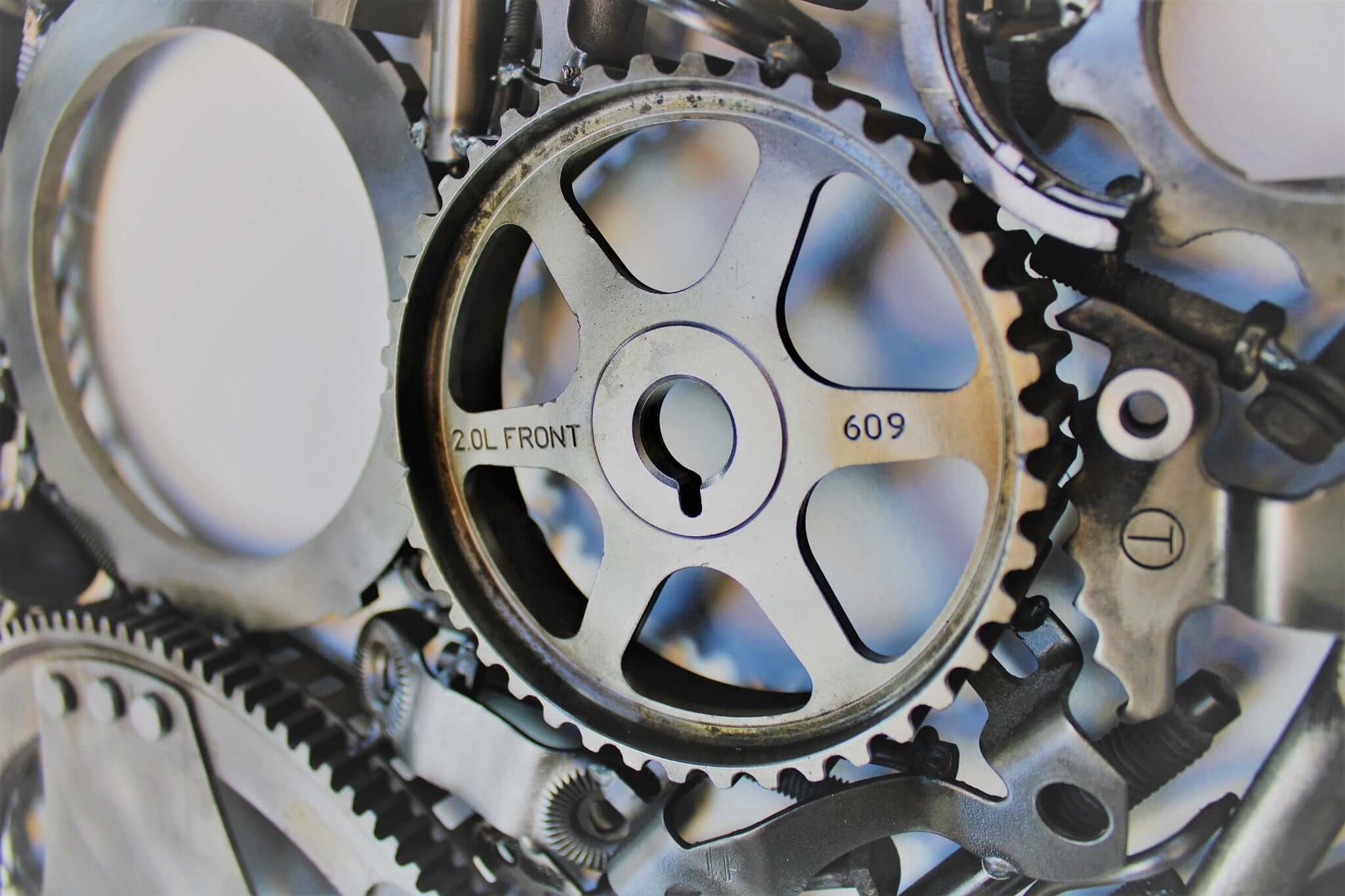 Handcrafted metal wall art piece outlined with timing chain and filled in entirely with polished genuine car engine components.