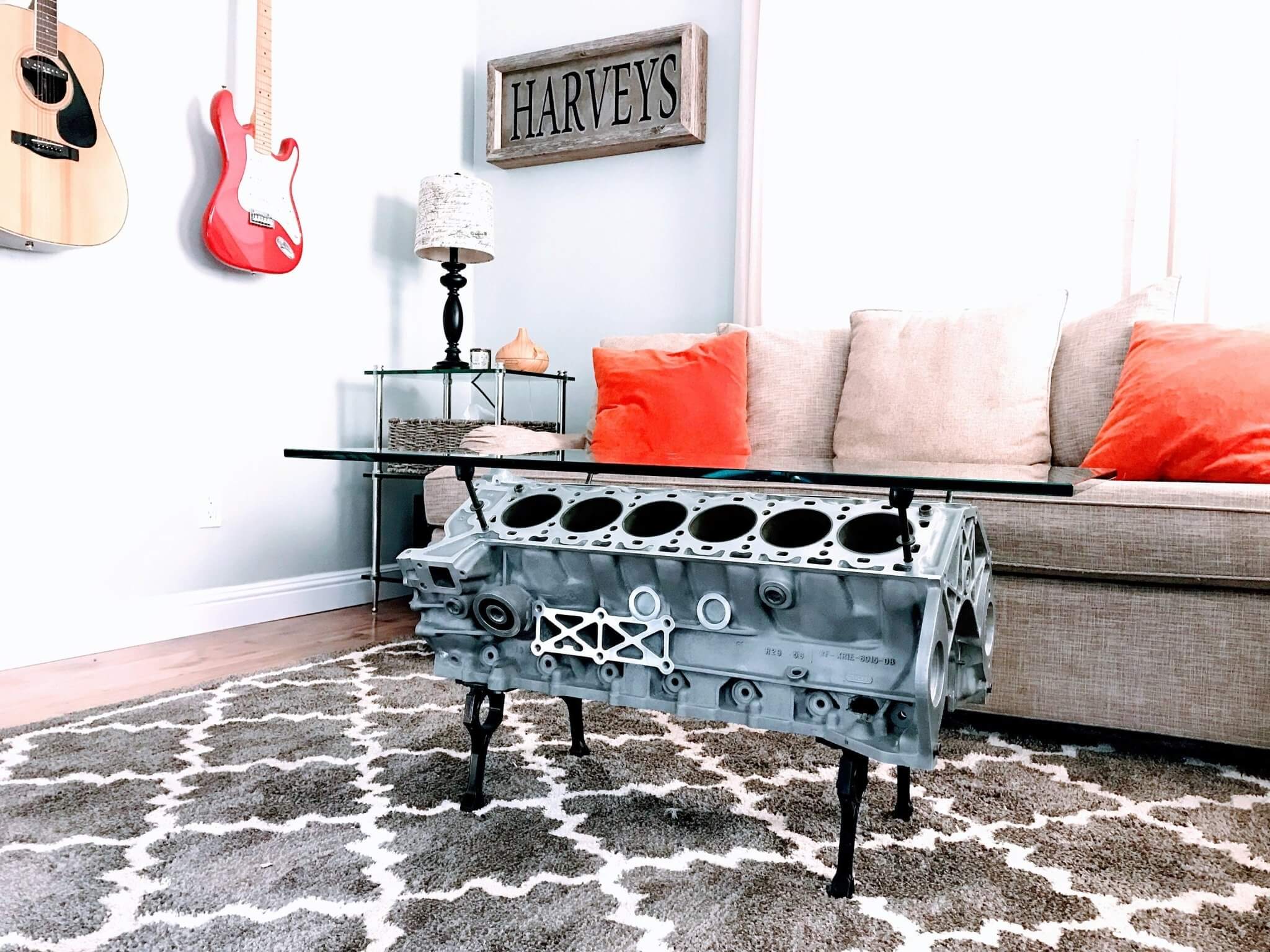 Coffee tables handcrafted from genuine car engines with various colored finishes, logos displayed, and glass top shapes.