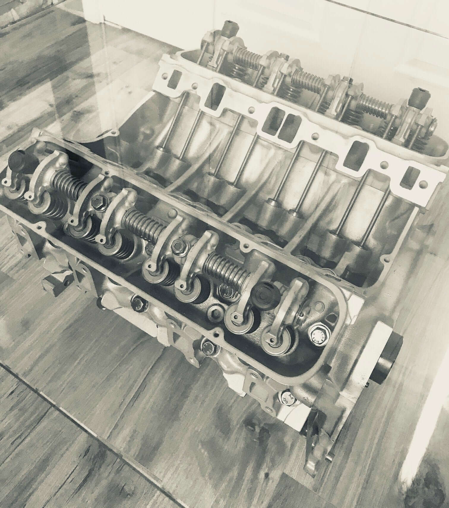 Coffee tables handcrafted from genuine car engines with various colored finishes, logos displayed, and glass top shapes.