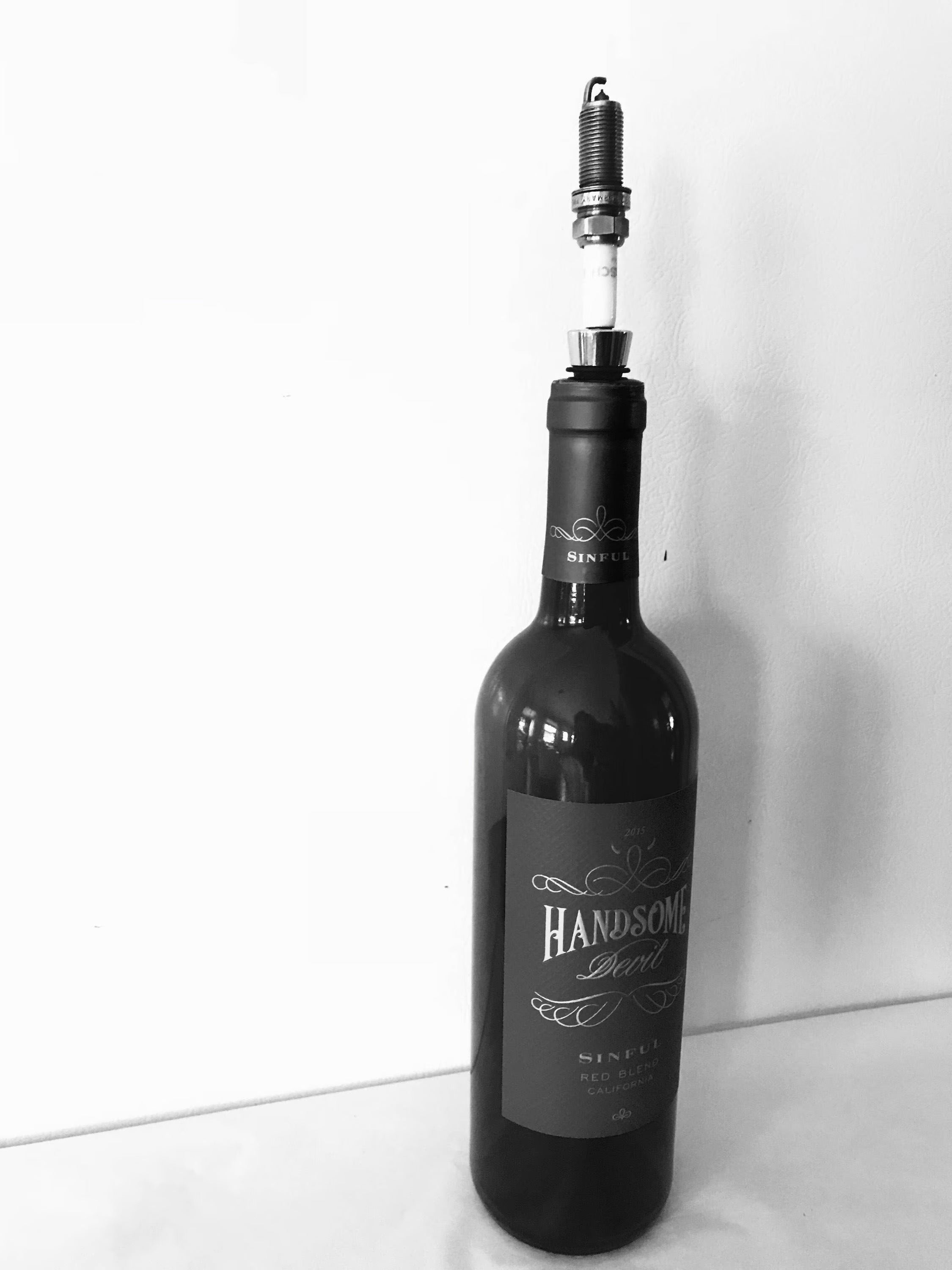 A bottle stopper made from a car's spark plug in use inside of a wine bottle.