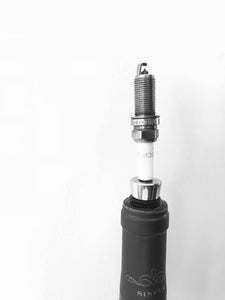 A bottle stopper made from a car's spark plug in use inside of a wine bottle.