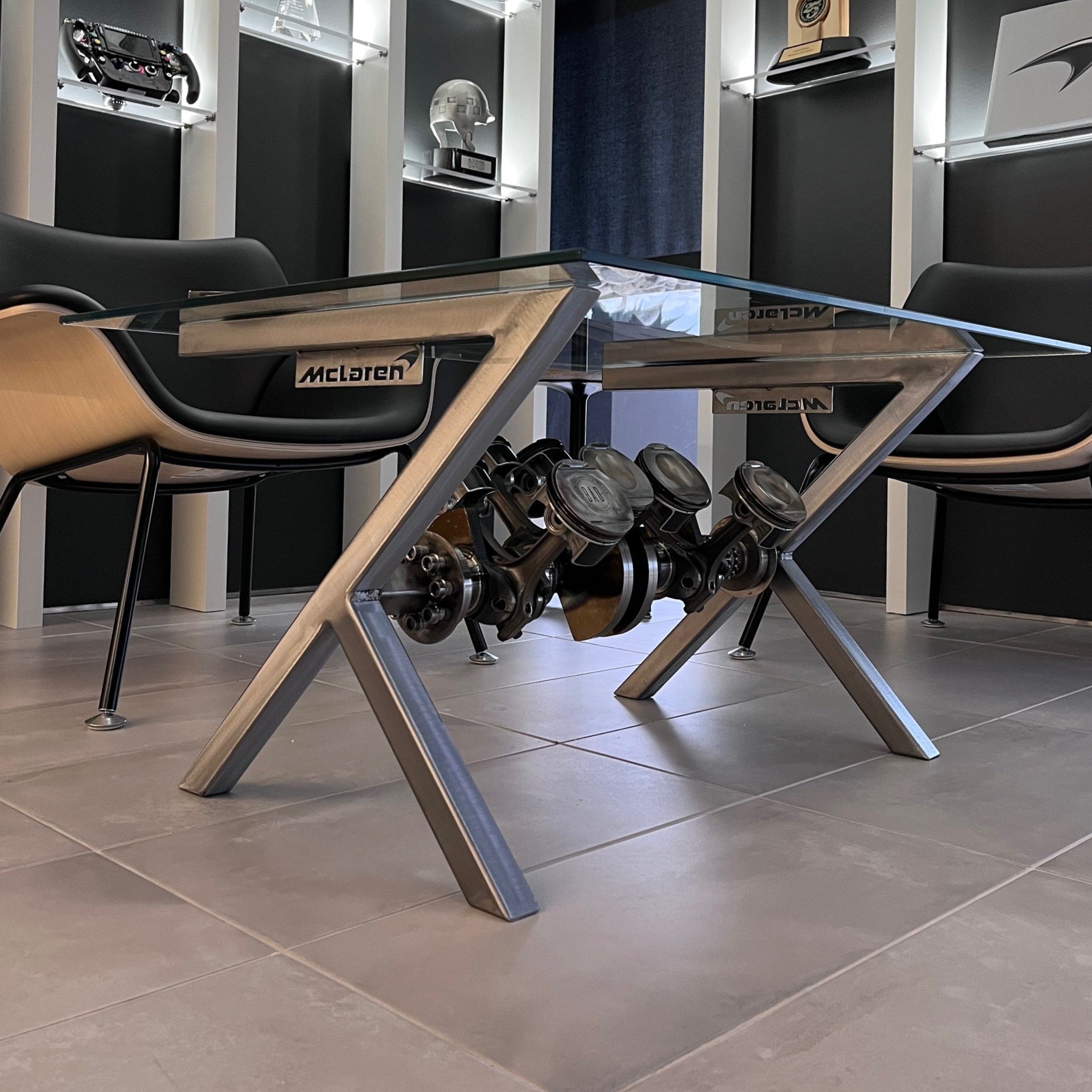 Modern office setup with a glass desk, chairs, and shelves displaying awards in a high-tech room.