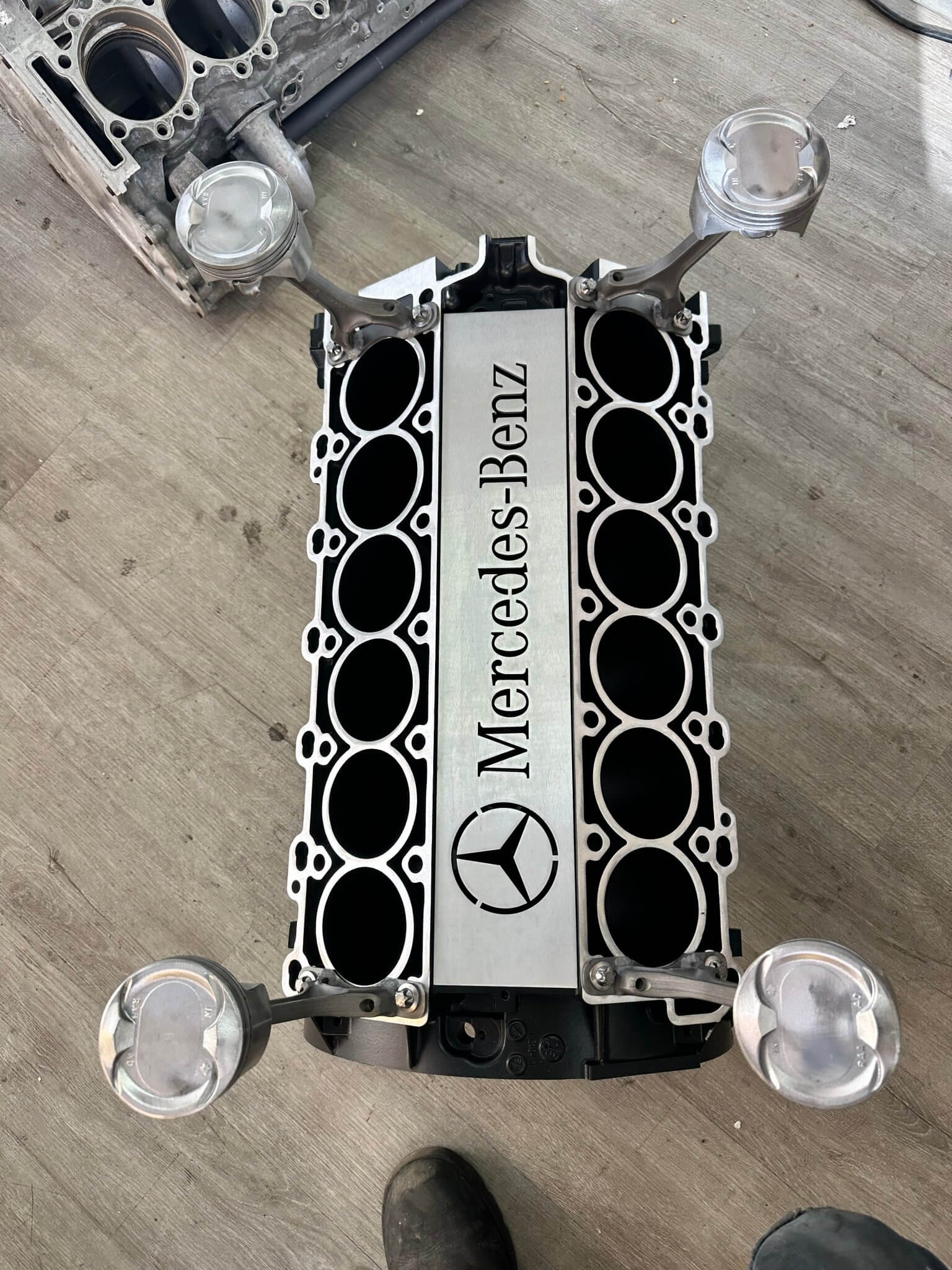 Coffee table handcrafted from a genuine Mercedes V12 car engine, finished in black and silver with the Mercedes-Benz logo displayed and a rectangular glass top.