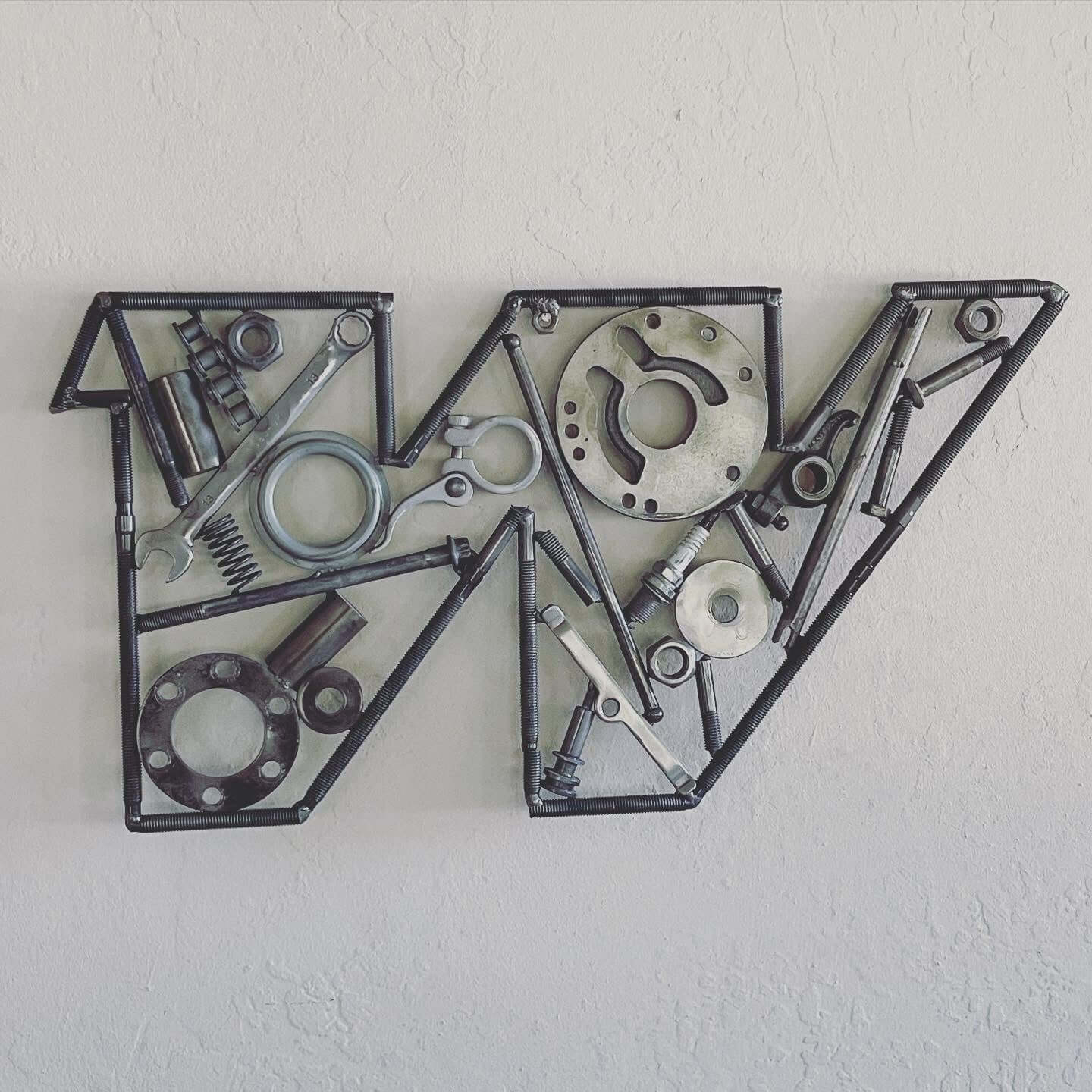 Hand-welded letter monogram decorations outlined with timing chain and filled in entirely with genuine polished car engine components with a glossy finish.