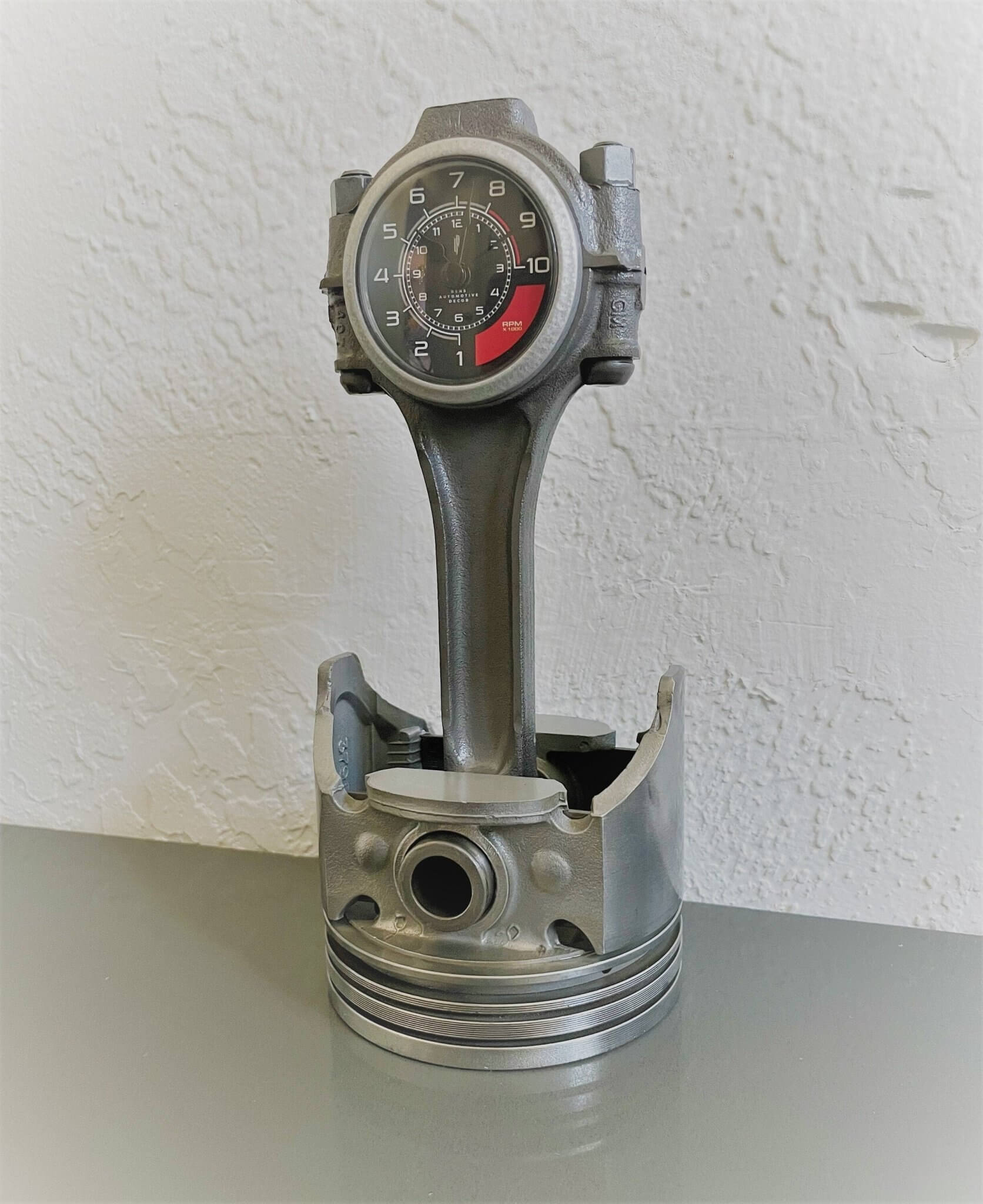 Tabletop clock handcrafted from a genuine car engine piston with a black and red clock face emulating a race car dashboard.