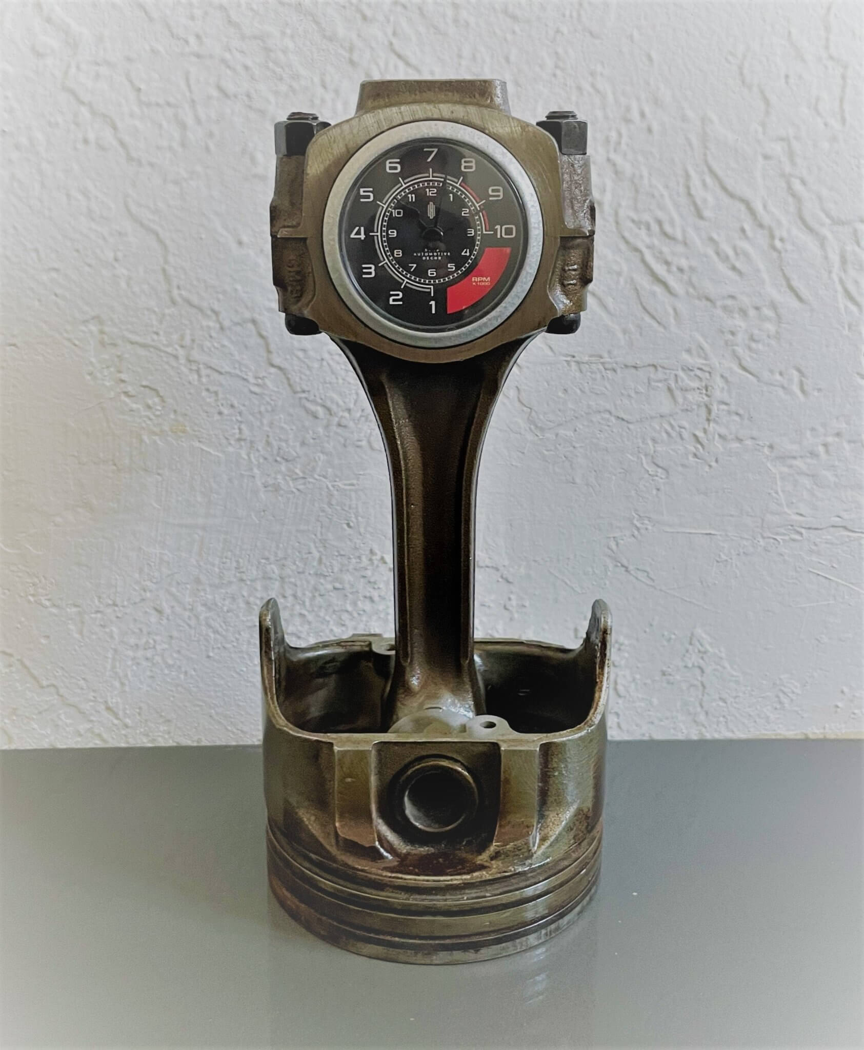 Tabletop clock handcrafted from a genuine car engine piston with a black and red clock face emulating a race car dashboard.