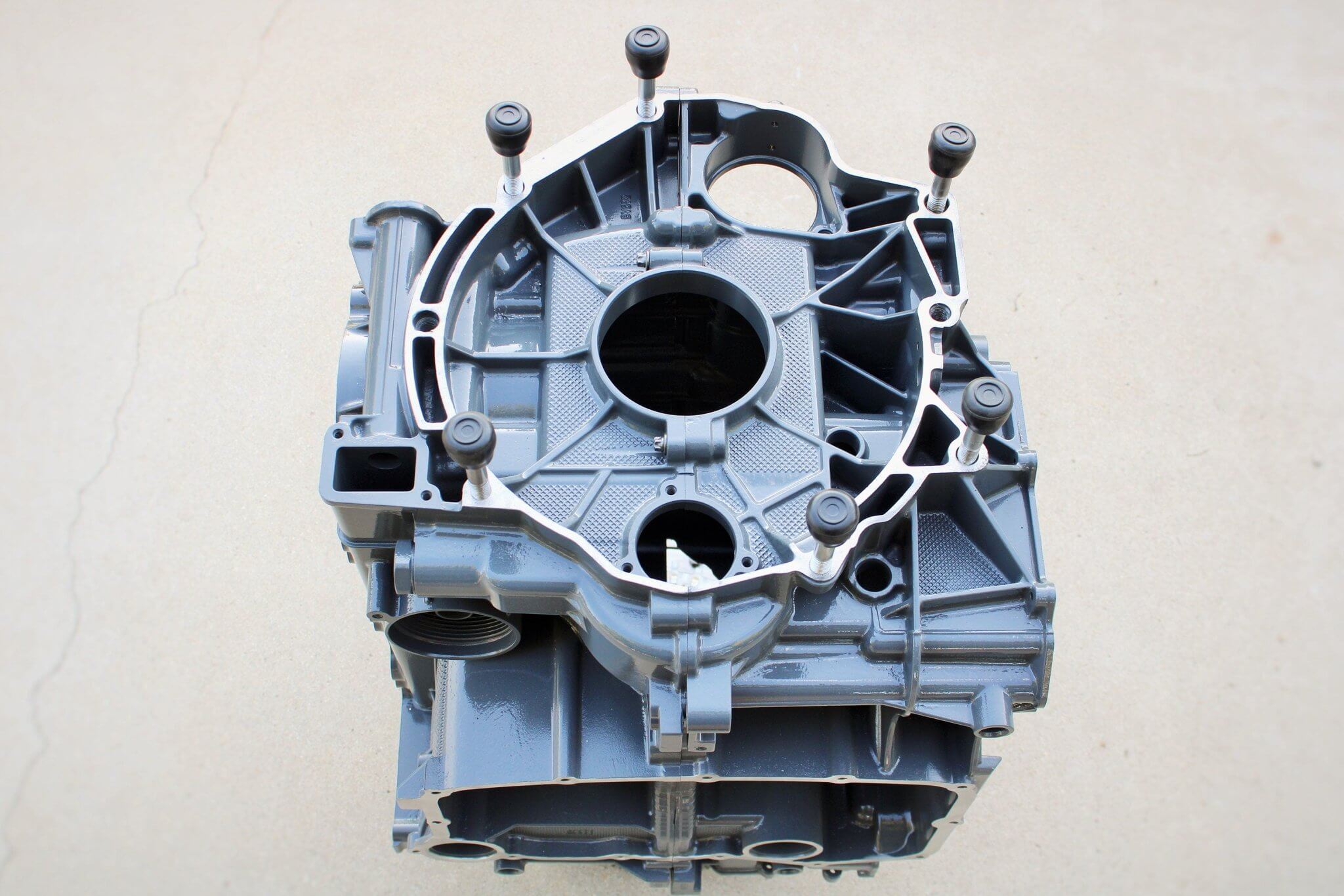 Wine rack table handcrafted from a genuine Porsche car engine, finished in gray and silver with a circular glass top.