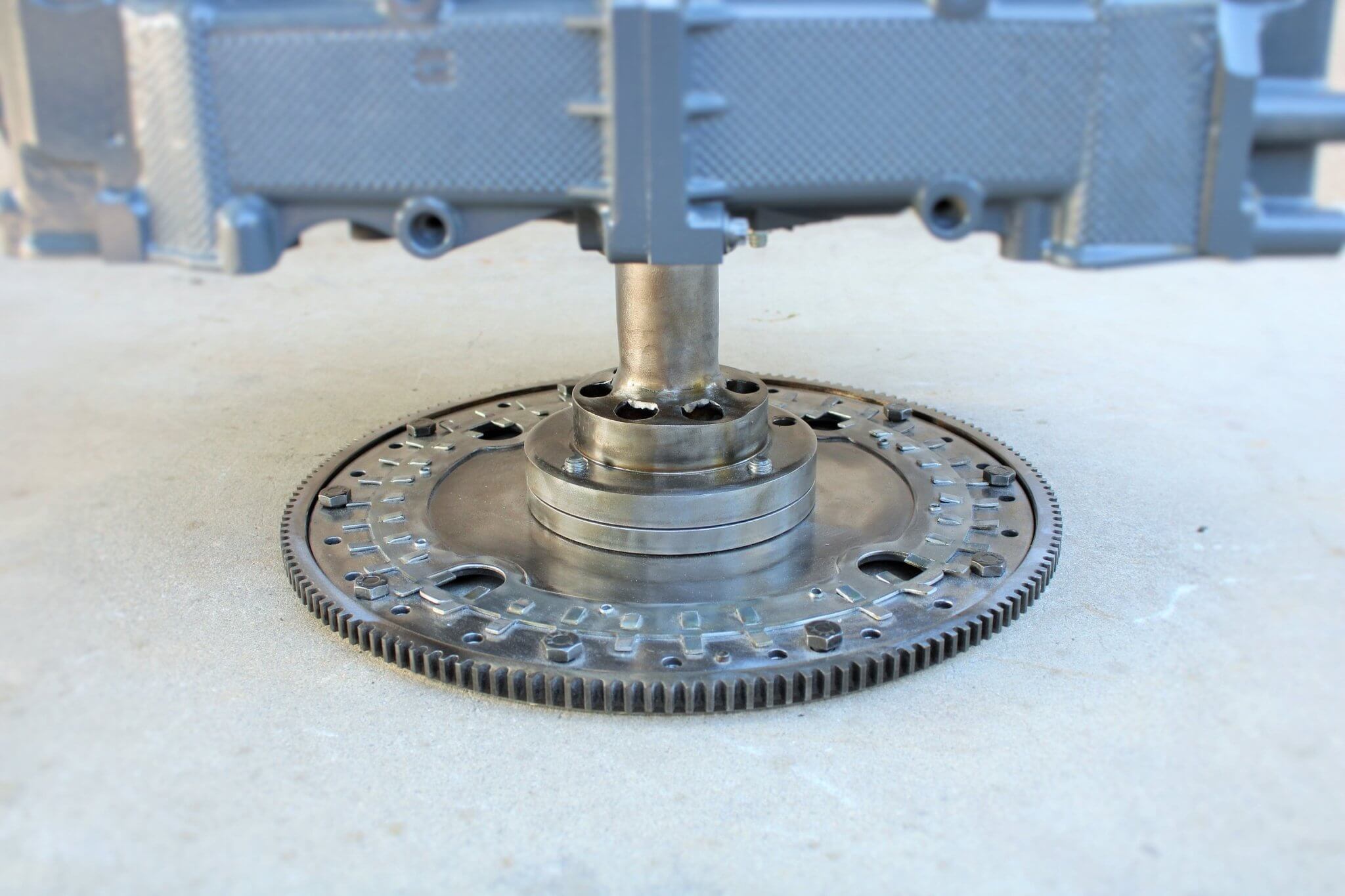 Wine rack table handcrafted from a genuine Porsche car engine, finished in gray and silver with a circular glass top.