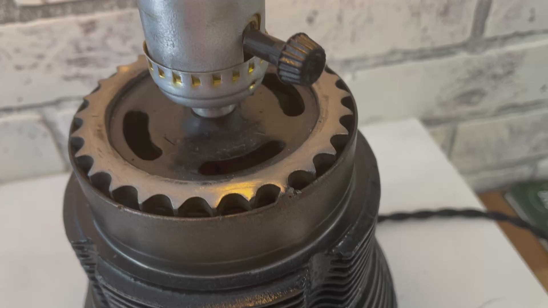 Video of a lamp with no shade made from a Porsche 911 car's air-cooled cylinder in a patina finish turned on.