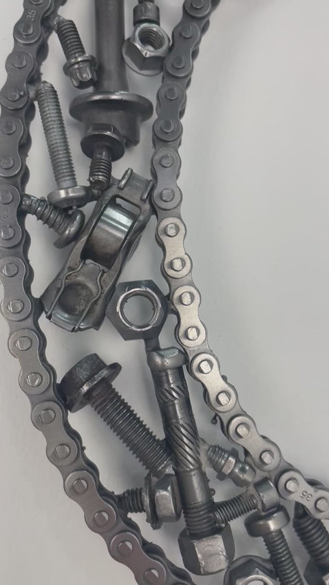 Video of a letter C made out of real car parts, outlined with a timing chain.