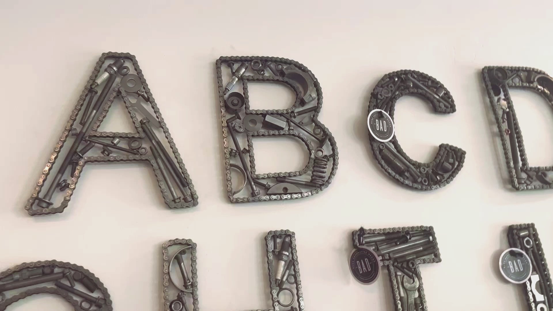 Video showcasing the entire alphabet of handcrafted car part letters hanging on a wall.