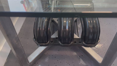 Video of a black and silver coffee table created from a Porsche engine intake manifold with a rectangular glass top and the Porsche logo displayed.