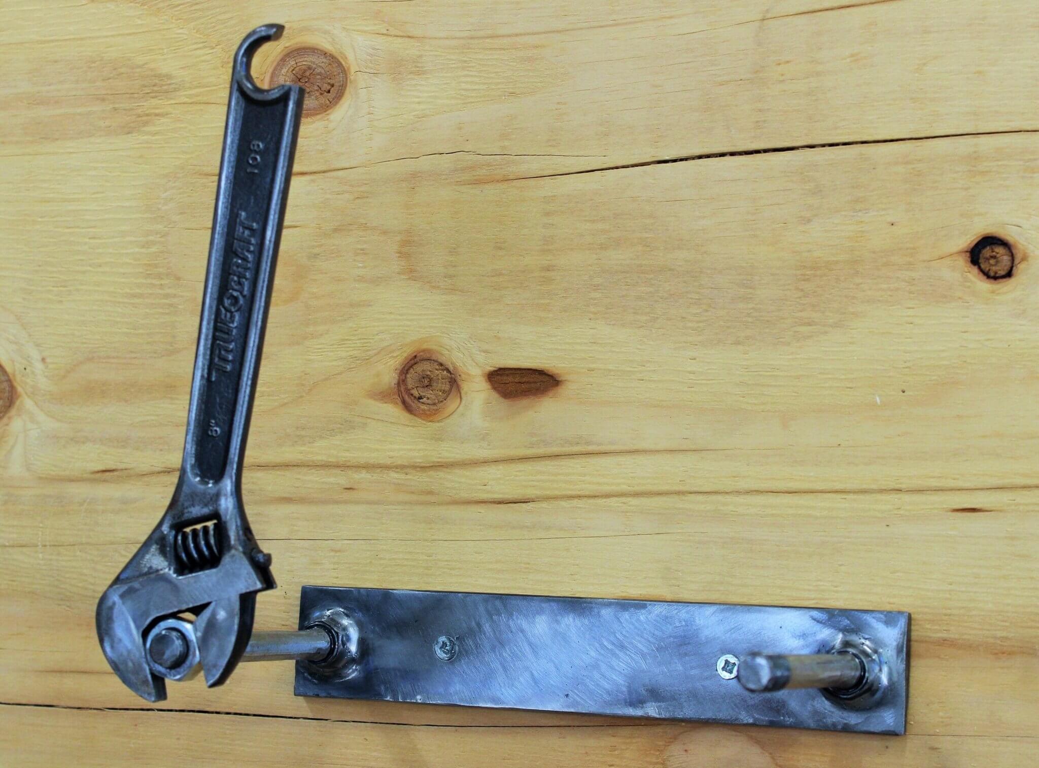 Toilet paper holder handcrafted from a real wrench with a polished finish and unique restocking mechanism.