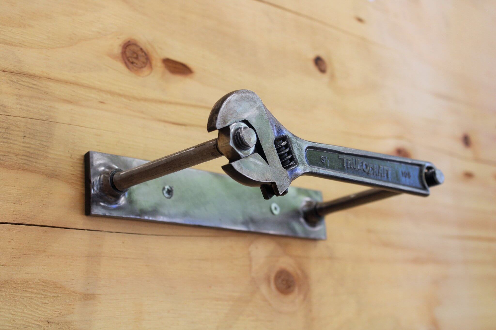 Toilet paper holder handcrafted from a real wrench with a polished finish and unique restocking mechanism.