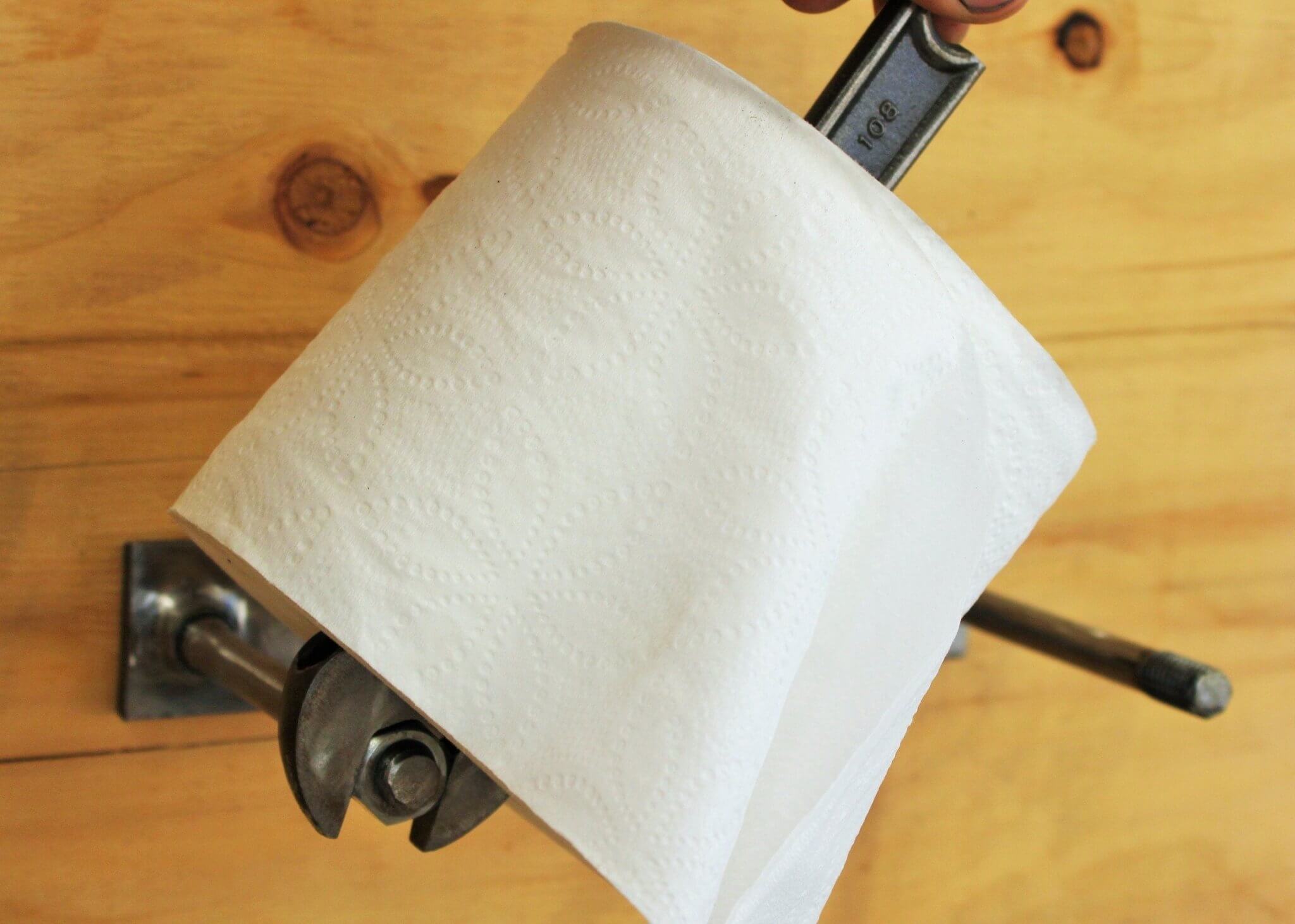 Toilet paper holder handcrafted from a real wrench with a polished finish and unique restocking mechanism.