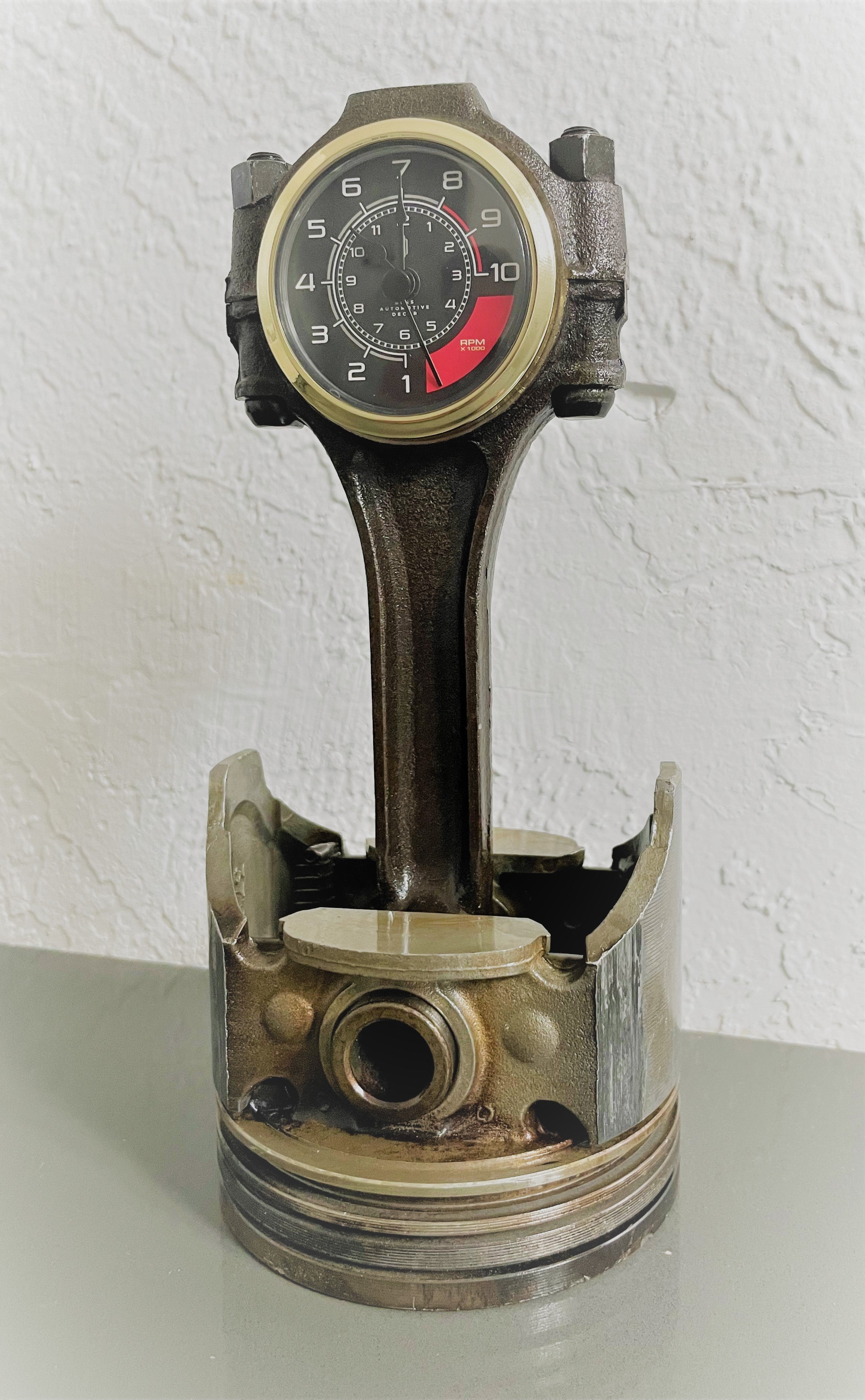 Desk clock made out of an Audi car engine piston, with a custom RPM clock face in a patina finish.
