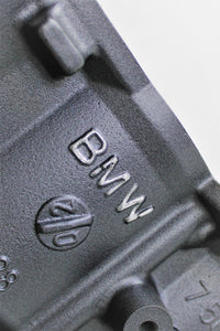 Close-up of the BMW logo on a BMW end table and wine rack finished in gunmetal grey.